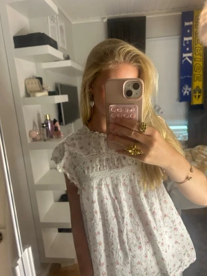 Vit blommig blus med spetsdetaljer - Säljer en blus med blommor och  spetsdetaljer, jättefin på sommaren, använd ca 2 gånger, original pris är 299kr❣️❣️