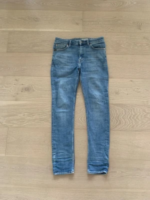 Tiger Of Sweden Jeans - Snygga blå slim fit jeans med klassisk femficksdesign och normalhög midja. Jeansen har en ljus tvätt och raka ben, perfekta för en avslappnad och trendig look. Tillverkade i denim med stretch för extra komfort. Storlek 28/30