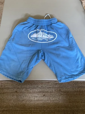 Ljus blå Corteiz shorts - Säljer ett par blåa loose shorts från Corteiz. De är i fint skick och är använd få gånger. 