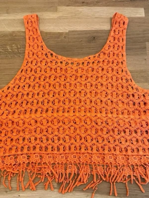 Orange virkad croppad linnetopp - Säljer en orange virkad linnetopp med fransar längst ner. Storlek S, passform XS-M🧡😍Använd 1 gång!