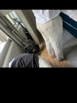 Beiga vida linnebyxor med fickor - Säljer ett par beiga linnebyxor med avslappnad passform och raka ben. Byxorna har sidofickor och bakficka med knappdetalj. Perfekta för en chill och stilren look. Materialet är luftigt linne som passar bra till sommaren.