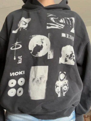 Svart hoodie med grafiska Y2K tryck  - Säljer en svart oversized hoodie med unika vita grafiska tryck och text på framsidan. Hoodien har en klassisk huva och ribbade muddar vid ärmslut och nederkant. Perfekt för dig som gillar streetwear och vill sticka ut med en cool design.
