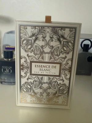 Essence de Blanc Eau de Parfum - Lyxig parfym i vit flaska med eleganta guld- och svartmönstrade detaljer samt en exklusiv guldfärgad kork. Förpackningen är stilren och har ett dekorativt mönster som ger en exklusiv känsla. Perfekt för dig som vill ha en sofistikerad doft. Har använt 3 spray så i princip ny. Inspererad utav lv imagination 
