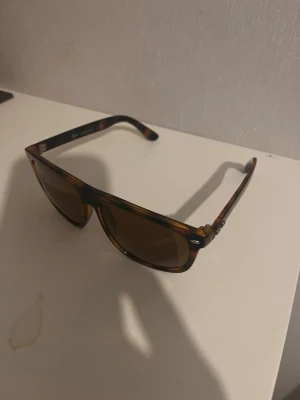 Rayban boyfriend  - Snygga solglasögon med brunt, sköldpaddsmönstrat båge och mörka linser. Perfekta för soliga dagar och ger en cool vibe till din outfit. Bågarna har en stilren design och passar de flesta ansiktsformer. Helt nya köpt på marknad