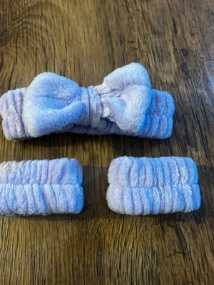 Ljuslila fluffigt hårband set - Säljer ett set med ett ljuslila fluffigt hårband med rosett och två matchande scrunchies. Tillverkade i mjuk plysch som känns skön mot huden. Perfekt för att hålla håret borta vid sminkning eller hudvård. Snygg pastellfärg som ger en söt look.
