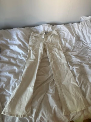 Vita bootcut jeans med brodyr - Säljer ett par vita bootcut jeans med snygg brodyr på bakfickorna. Jeansen har klassisk femficksmodell, bälteshällor och dragkedja. Använt max 2 gånger, säljer då det är lite för korta på mig som är 167cm. Strl S, längd short. 