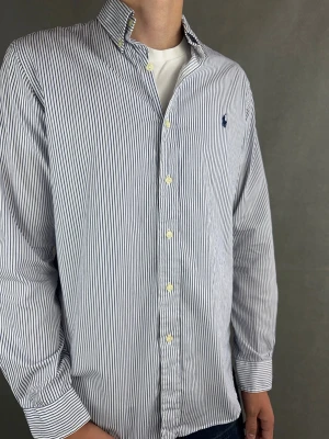 Ralph Lauren skjorta - Ralph Lauren Skjorta Märke: Polo Ralph Lauren Storlek: M Passform: Färg: Blåvit randig Skick: Bra Beskrivning: liten fläck. Modellen på bilden: 183 cm / 74 kg