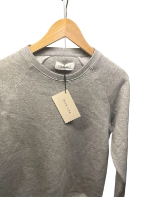 Grå sweatshirt från Pier One - Klassisk grå sweatshirt från Pier One i mjuk bomullsmix. Tröjan har rund halsringning och långa ärmar, perfekt för en chill och enkel stil. Passar till allt och är superenkel att matcha med jeans eller joggers.