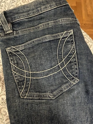Mörkblå bootcut jeans från gina tricot  - Säljer ett par mörkblå bootcut jeans från gina tricot med ikonisk kontrastsöm på bakfickan. Jeansen har låg midja med bootcut passform. Tillverkade i slitstark denim. Perfekta för dig som gillar en avslappnad men snygg stil. Nyskick, endast provade hemma. 