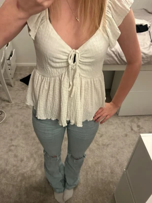 Vit topp med knyt - Vit topp med knyt fram och volanger nedtill💕 Tveka inte att skriva om du är intresserad eller vill ha fler bilder. Pris kan diskuteras❤️