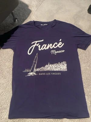 Mörkblå t-shirt Molentis Monaco print - Snygg mörkblå t-shirt från Molentis med vit print framtill som visar texten 'France Monaco' och en illustration av Monaco. T-shirten har klassisk passform och korta ärmar. Perfekt för dig som gillar stilrena tryck och fransk vibe. Använd en gång, hör av dig vid minsta fråga