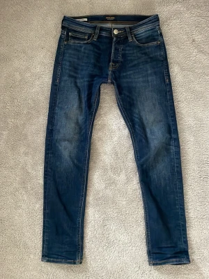 Mörkblå slim fit jeans från Jack & Jones - Snygga mörkblå slim fit jeans från Jack & Jones med storlek W28 L30. Har inte haft på mig dom så mycket, de är inte riktigt min storlek så de har nu legat i garderåben en stund. 