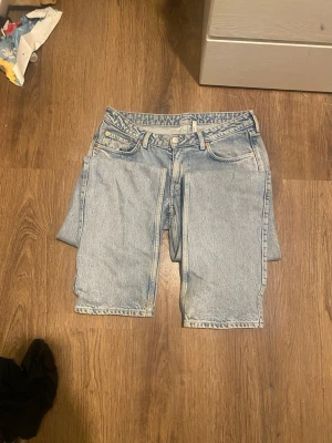 Ljusblå jeans i denim - Säljer ett par ljusblå jeans i klassisk femficksmodell. De har låg midja, raka ben och är gjorda i ett slitstarkt denimtyg. Perfekta för en avslappnad och trendig look. Passar dig som gillar vintagekänsla och enkel stil. Modell Arrow från Weekday, storlek 30/34