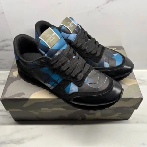 Valentino rockrunners  - Snygga sneakers från Valentino med blå, grå och svarta camo-detaljer. Skorna har svarta snören, svart sula och en cool kontrast mellan läder och textil. Märkeslogga på plösen och unik design som sticker ut. Priset kan diskuteras.
