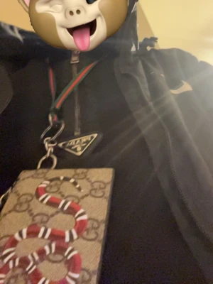 Gucci plånbok med orm och monogram - Säljer en snygg Gucci plånbok i beige canvas med klassiskt GG-monogram och en röd, vit och svart orm på framsidan. Plånboken har dragkedja upptill och medföljande grön-röd handledsrem. Kommer med original ask och dustbag.