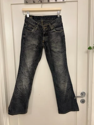 Gråa bootcut Lee jeans  - Säljer ett par gamla vintage Lee bootcut jeans med en tydlig söm och snygga detaljer! De är mörkgråa med mörka detaljer!