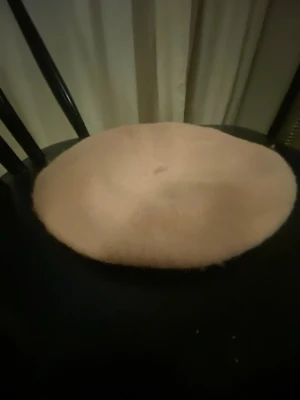 Ljusrosa basker i ull - Säljer en ljusrosa basker i klassisk modell. Hatten är tillverkad i mjuk ull och har en rund, platt form som ger en tidlös look. Perfekt accessoar för att lyfta din outfit med en fransk touch.