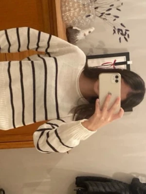 Vit stickad tröja med svarta ränder - Säljer en vit stickad tröja med svarta horisontella ränder. Tröjan har en croppad passform, rund halsringning och ribbade muddar vid ärmslut och nederkant. Perfekt för en avslappnad och trendig look.