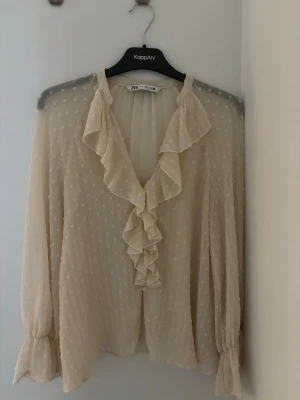 Beige volangblus från Zara - Supersöt beige blus från Zara med volangdetaljer längs v-ringningen och framtill. Säljer då jag aldrig änvänt den🩷