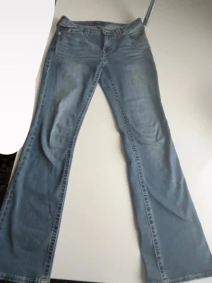True religion  - Säljer ett par ljusblå jeans med utsvängda ben och klassisk femficksmodell. Jeansen har hög midja och är tillverkade i mjukt denimtyg. Perfekta för dig som gillar retrostil och vill ha ett par bekväma och trendiga jeans. Modell Becca från Nelly 