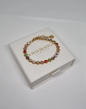 Färgglatt armband - Snyggt armband i guldton  med runda länkar dekorerade med glittrande stenar i flera färger som rött, grönt, blått, lila och vitt. Perfekt för dig som gillar färg och vill ha något som sticker ut. Justerbar längd med kedja och liten rund bricka vid låset. Lådan ingår ej.