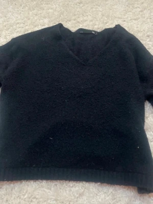 Svart stickad V-ringad tröja - Mysig marinblå stickad tröja med V-ringning och långa ärmar. Tröjan har en enkel och stilren design med ribbstickad nederkant. Perfekt för lager-på-lager och passar till det mesta i garderoben.