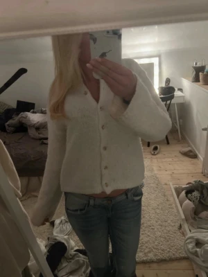 Vit kofta från BikBok med knappar - Mysig vit kofta från BikBok med träfärgade knappar framtill. Koftan har en rak passform, långa ärmar och är stickad i ett mjukt material. Perfekt att slänga över en topp för en chill look.