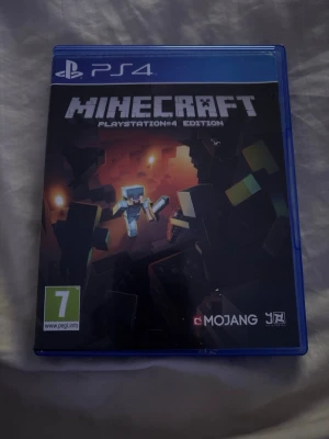 Minecraft PlayStation 4 Edition - Minecraft PlayStation 4 Edition är ett ikoniskt sandlådespel där du kan bygga, utforska och överleva i en blockig värld. Spelet kommer i ett blått plastfodral och har en färgstark framsida med pixelgrafik och äventyrstema.