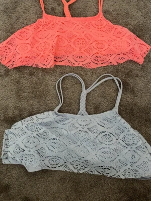Två virkade bikinioverdelar i pastell - Säljer två snygga bikinioverdelar från Lindex i återvunnen polyester. En är ljusrosa och den andra ljusblå, båda med virkad look och flätade axelband. Perfekta för stranden eller poolen och ger en trendig boho-vibe.