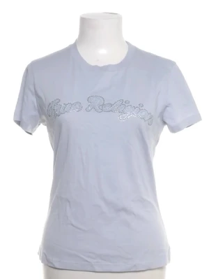 Ljusblå True Religion t-shirt - Snygg ljusblå t-shirt från True Religion med glittrande logga framtill. Klassisk rund halsringning och korta ärmar. Tillverkad i mjuk bomull för en bekväm känsla och perfekt passform.