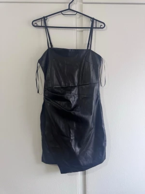Svart skinnklänning  - En skinnklänning i stl S som aldrig är använd säljs för 150 kr.