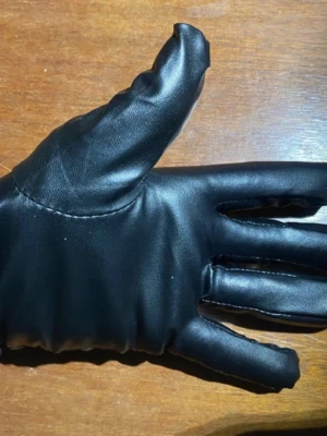 Svarta skinnhandskar med sömmar - Snygga svarta handskar i skinnimitation med dekorativa sömmar på ovansidan. Perfekta för att hålla händerna varma och ge en stilren look. Passar till de flesta outfits och är lätta att matcha.
