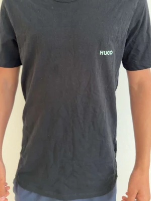 Svart t-shirt från HUGO - Säljer en svart t-shirt från HUGO i storlek M. T-shirten har en enkel och clean design med HUGO-loggan tryckt på bröstet. Tillverkad i mjuk bomull och har klassisk passform med korta ärmar och rund hals.