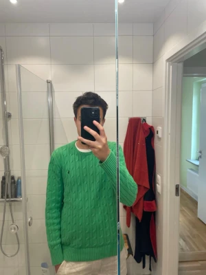 Grön kabelstickad  Polo Ralph Lauren - Säljer denna riktigt snygga gröna kabelstickade Ralph Lauren tröjan. En färg som passar perfekt nu under sommaren. I ett toppenskick! Barnstorlek L vilket motsvarar herr XS/S. Modellen är 181cm. Kontakta vid funderingar!