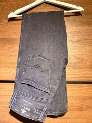 Grå jeans från Replay - Snygga grå jeans från Replay med klassisk femficksdesign och raka ben. Jeansen har diskreta sömmar och en stilren look, perfekta för en trendig vardagsstil. Materialet är mjukt denim som ger en bekväm känsla hela dagen.