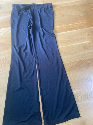 Svarta utsvängda leggings - Säljer ett par svarta leggings med utsvängda ben. De är mjuka och stretchiga, perfekta för en avslappnad och trendig look. Passformen är tight upptill och vidare nedtill. Inget synligt märke.