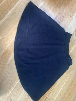 Svart kortkjol från SHEIN - En svart, enkel och stilren kortkjol från SHEIN. Kjolen har en lätt utställd form och är gjord i ett mjukt, stretchigt material som består av polyester och elastan. Perfekt att matcha med en crop top eller hoodie för en chill look.