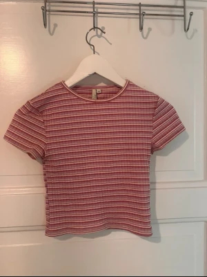Randig ribbad topp från nelly - Kortärmad topp från nelly i ribbad bomull med smal passform. Toppen har ett randigt mönster i rött, vitt och rosa samt rund halsringning. Perfekt till jeans eller kjol för en avslappnad look.