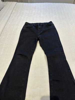 Svarta bootcut jeans från VILA - Säljer ett par svarta bootcut jeans från VILA med klassisk femficksdesign och hällor för skärp. Jeansen har en snygg tvättad look och är tillverkade i mjukt stretchigt denimtyg som sitter skönt hela dagen.