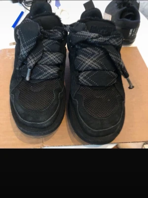 Svarta sneakers från UGG - Säljer ett par svarta sneakers från UGG med grova, mönstrade skosnören och meshdetaljer på ovandelen. Skorna har en robust sula och insidan är fodrad med mjukt material för extra komfort. Perfekta för dig som gillar streetwear och en chunky look.