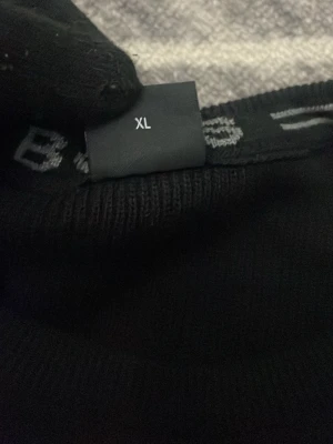 Svart tröja från BOSS, XL - Snygg svart tröja från BOSS i storlek XL. Tröjan har en klassisk rund halsringning med ribbstickade detaljer och diskret BOSS-logga på insidan av kragen. Perfekt för en stilren och enkel look.PRIS KAN DISKUTERAS 