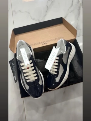 Blå och vita sneakers med meshdetaljer - Snygga sneakers i blått och vitt med glansiga partier och meshdetaljer på sidorna. Skorna har vita snören och en vit sula med sportig känsla. Perfekta för dig som gillar en fräsch och modern stil. För mer info kontakta mig .
