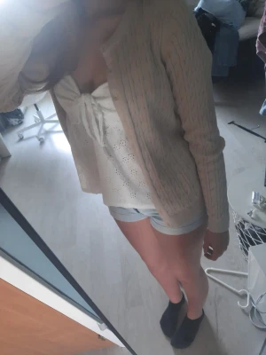 Beige kabelstickad kofta - Snygg beige kabelstickad kofta med rund hals och knappar framtill. Koftan har långa ärmar och ribbade muddar vid ärmslut och nederkant. Perfekt att slänga över en topp för en chill look.