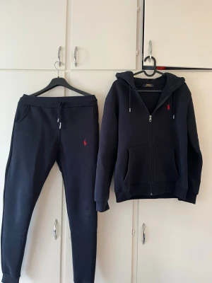 Mörkblå mjukisbyxor från Polo Ralph Lauren - Snygga mörkblå mjukisbyxor från Polo Ralph Lauren med dragsko i midjan och fickor på sidorna. Byxorna har det klassiska röda Polo-logotrycket på låret och är gjorda i mjukt bomullsmaterial för maximal komfort. Det står att de är large men jag tror att det är large i barn storlek, eftersom de passar mig perfekt och jag brukar ha S.