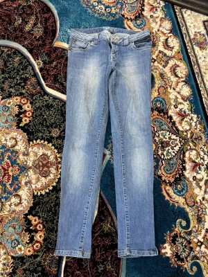 Ljusblå raka jeans med slitningar - Säljer ett par ljusblå jeans med raka ben och diskreta slitningar framtill. Jeansen har klassisk femficksmodell, bälteshällor och dragkedjegylf. Materialet är denim i bomull och passformen är smal men inte supertight.