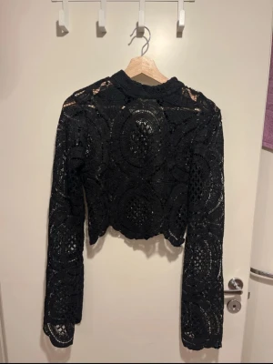 Svart croppad tröja  - Säljer en virkad svart croppad tröja i spets med lång ärm och hög halsringning. Som ny, använd fåtal gånger 🥰.
