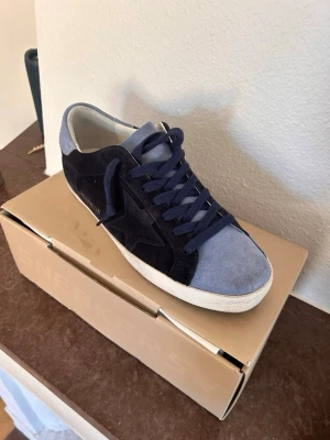Golden Goose - Snygga sneakers från Golden Goose i mocka med mörkblå och ljusblå paneler. Skorna har klassisk låg profil, matchande blå skosnören och vit sula. Perfekta för dig som gillar stilrena och trendiga detaljer.