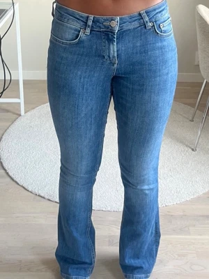 Blå bootcut jeans från Zara - Snygga blå bootcut jeans med klassisk femficksdesign och lätt utsvängda ben. Jeansen har en medelhög midja och är tillverkade i stretchigt denimtyg för extra komfort. Perfekta för en avslappnad och trendig look.