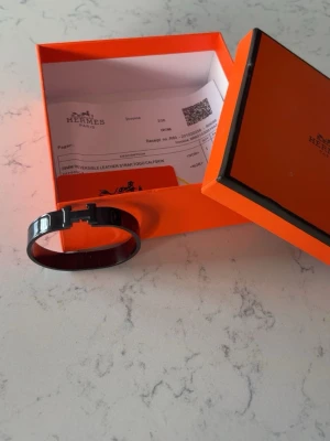 svart läderarmband - Snyggt svart läderarmband med metallspänne. Armbandet har en stilren och modern design och kommer i original orange box. Perfekt accessoar för dig som gillar exklusiva detaljer och klassisk stil.