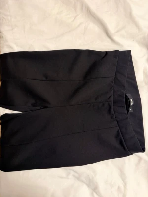 Svarta kostymbyxor från bikbok - Säljer ett par klassiska svarta kostymbyxor från bikbok. Byxorna har raka ben, pressveck framtill och en enkel, stilren design. Perfekta för en clean och snygg look. Materialet känns mjukt och har lite stretch för extra komfort.